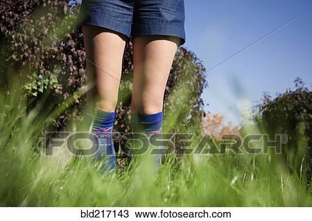 Stock Image - Woman wearing shorts and socks in tall grass. Fotosearch