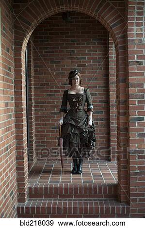 Stock Photo - Woman wearing vintage gown in brick archway. Fotosearch