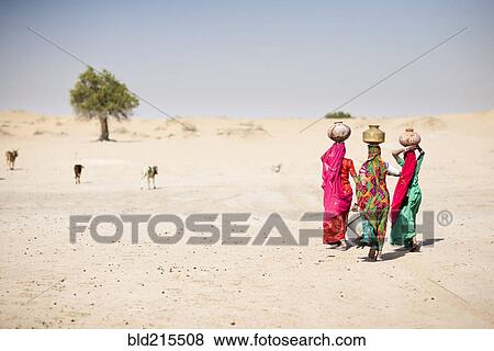 Stock Photo - Women carrying water in traditional baskets in remote desert. Fotosearch