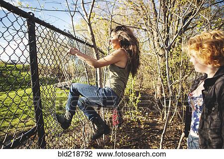 Women climbing through hole in chain-link fence View Large Photo Image Stock Image - Women climbing through hole in chain-link fence. Fotosearch