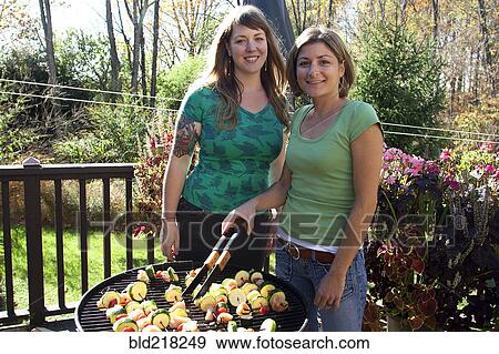 Stock Photo - Women grilling kebabs in backyard. Fotosearch