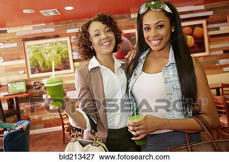 Stock Photo - Women having juice together in cafe. Fotosearch