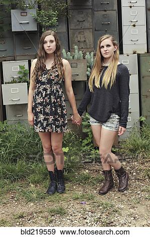 Stock Photo - Women holding hands near dilapidated office drawers in garden. Fotosearch