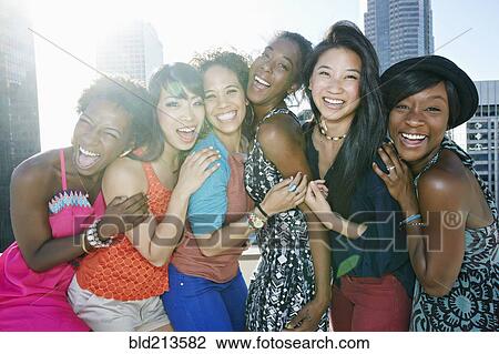 Stock Image - Women hugging on urban rooftop. Fotosearch