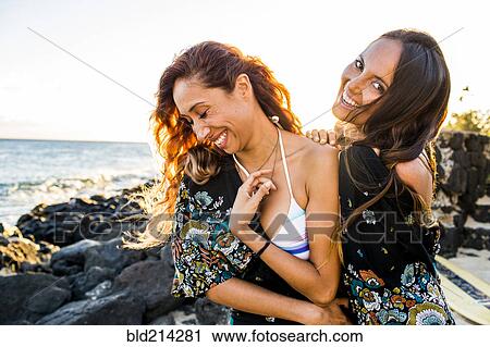 Stock Image - Women laughing on rocky beach. Fotosearch
