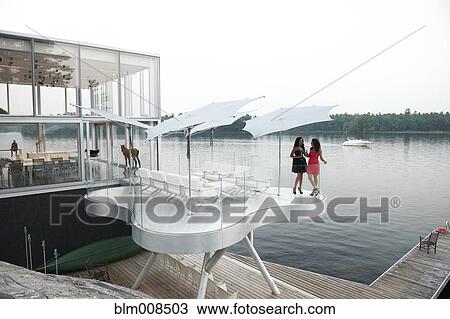 Women on balcony of modern lake house View Large Photo Image Stock Image - Women on balcony of modern lake house. Fotosearch