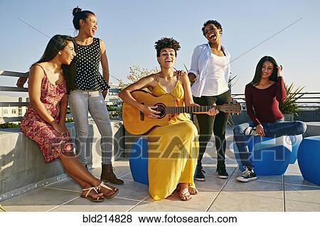 Stock Photo - Women playing music and singing on urban rooftop. Fotosearch