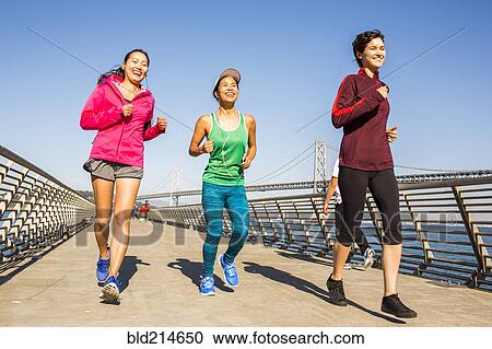 Stock Image - Women running on urban footbridge, San Francisco, California, United States. Fotosearch