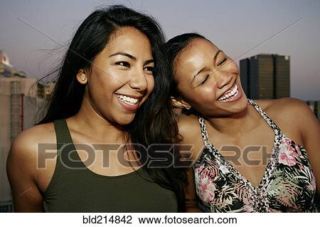 Stock Image - Women smiling on urban rooftop. Fotosearch