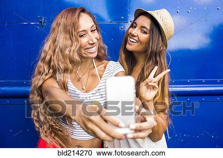 Stock Image - Women taking cell phone photograph together. Fotosearch