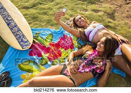 Stock Photograph - Women taking cell phone photograph together on blanket. Fotosearch