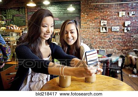 Women taking selfie with cell phone at cafe table View Large Photo Image Stock Photo - Women taking selfie with cell phone at cafe table. Fotosearch