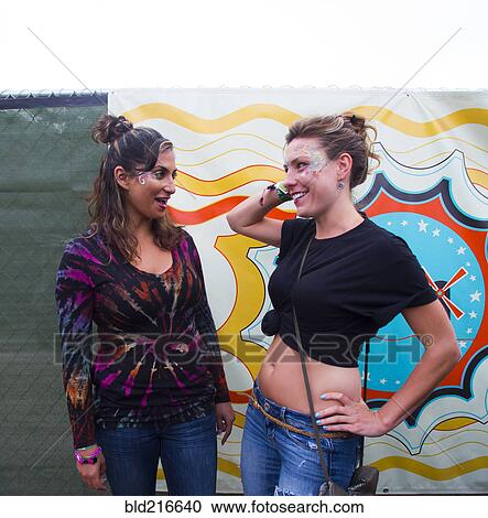 Stock Image - Women talking near multicolor mural. Fotosearch
