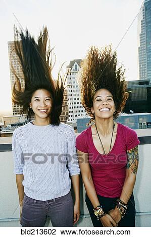 Women tossing their hair on urban rooftop View Large Photo Image Stock Image - Women tossing their hair on urban rooftop. Fotosearch