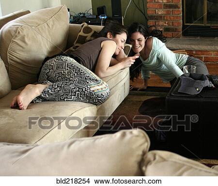 Women using cell phone in living room View Large Photo Image Picture - Women using cell phone in living room. Fotosearch
