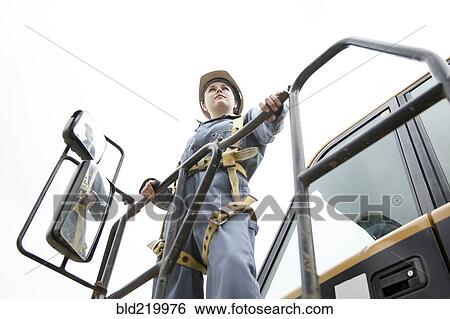 Stock Photograph - Worker wearing harness at construction site. Fotosearch