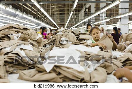 Stock Photograph - Workers folding clothing in garment factory. Fotosearch
