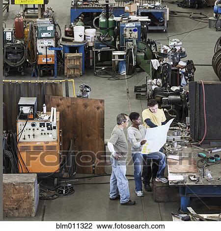Workers looking at blueprints in factory View Large Photo Image Stock Image - Workers looking at blueprints in factory. Fotosearch
