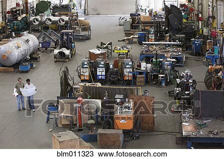 Workers looking at blueprints in factory View Large Photo Image Stock Image - Workers looking at blueprints in factory. Fotosearch
