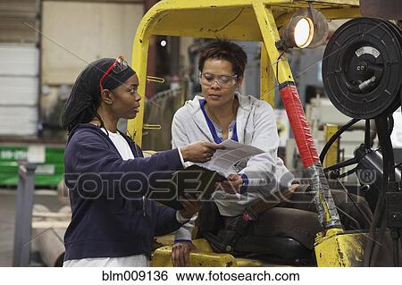 Workers looking at clipboard in factory View Large Photo Image Stock Photograph - Workers looking at clipboard in factory. Fotosearch