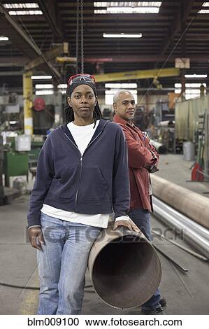 Workers standing near metal pipes in factory View Large Photo Image Stock Image - Workers standing near metal pipes in factory. Fotosearch