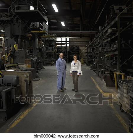 Stock Image - Workers standing together in factory. Fotosearch