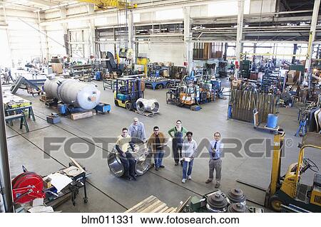Stock Image - Workers standing together in factory. Fotosearch