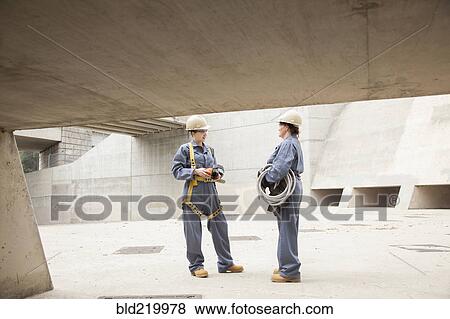 Stock Photo - Workers talking at construction site. Fotosearch