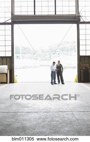 Stock Photography - Workers talking together in warehouse. Fotosearch
