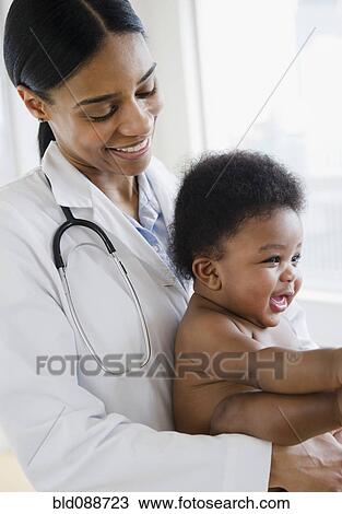 Stock Image - African American doctor holding baby boy. Fotosearch