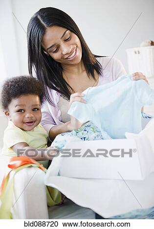 Stock Image - African American mother and baby boy opening gift. Fotosearch