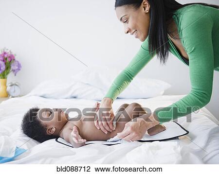 Stock Image - African American mother changing son's diaper. Fotosearch