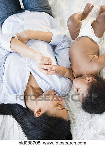 Stock Photography - African American mother laying with baby boy. Fotosearch