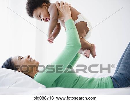 Stock Image - African American mother lifting baby boy. Fotosearch