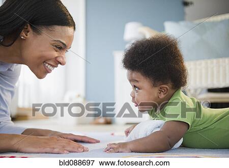 Stock Photo - African American mother playing on floor with baby boy. Fotosearch