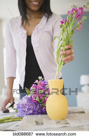 Stock Photo - African American woman arranging flowers in base. Fotosearch