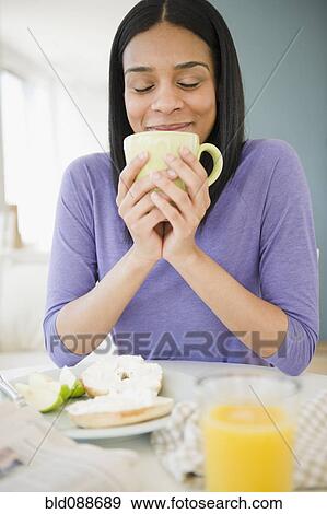 Stock Photo - African American woman drinking coffee with breakfast. Fotosearch