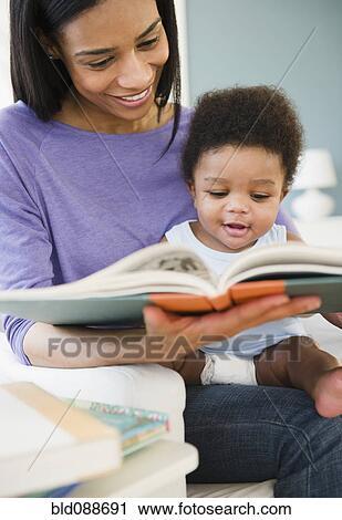 Stock Image - African American woman reading to baby boy. Fotosearch