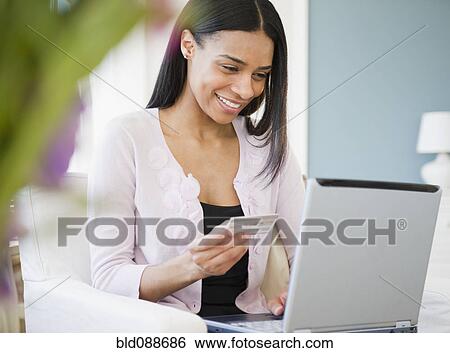 Stock Photograph - African American woman shopping online with credit card. Fotosearch