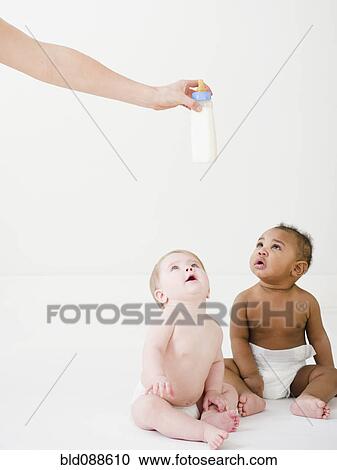 Babies looking up at hand holding bottle View Large Photo Image Stock Image - Babies looking up at hand holding bottle. Fotosearch