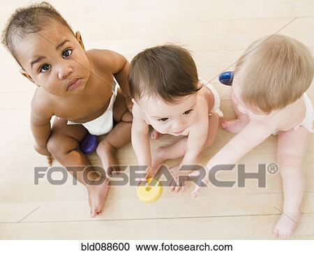 Stock Image - Babies playing together on floor. Fotosearch