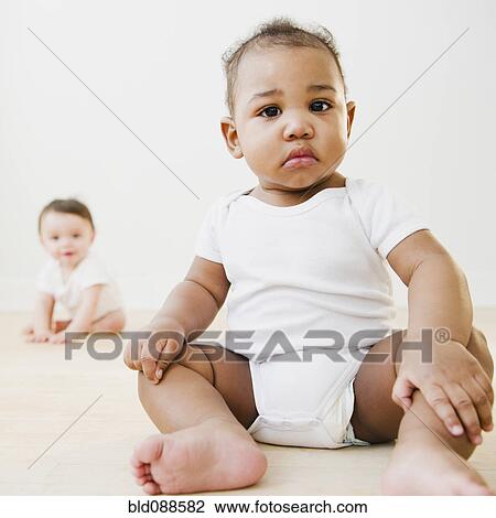 Stock Image - Black baby sitting on floor. Fotosearch