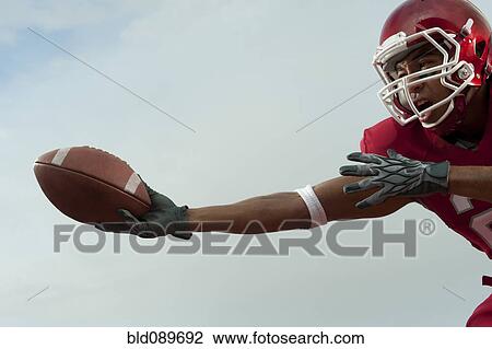 Stock Image - Black football player catching football. Fotosearch