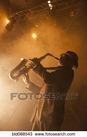 Stock Image - Black musician playing saxophone on stage. Fotosearch