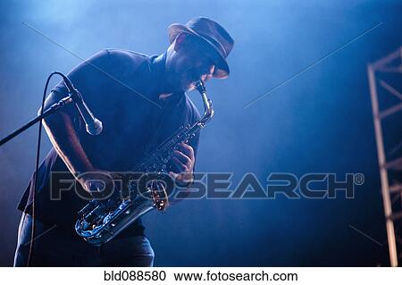Stock Image - Black musician playing saxophone on stage. Fotosearch