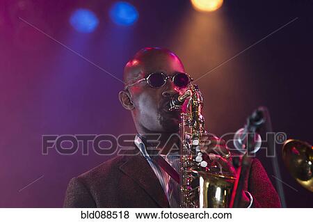 Stock Photo - Black musician playing saxophone on stage. Fotosearch