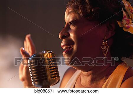 Stock Image - Black woman singing into microphone. Fotosearch