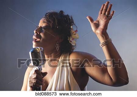 Stock Image - Black woman singing into microphone. Fotosearch