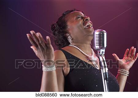 Stock Image - Black woman singing on stage. Fotosearch