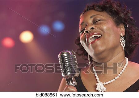 Stock Image - Black woman singing on stage. Fotosearch
